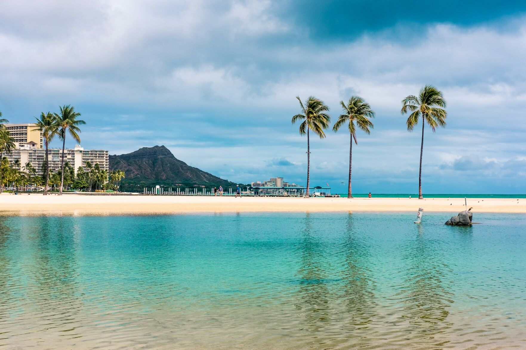 This serene ocean with palm trees and mountains is on the island of Oahu